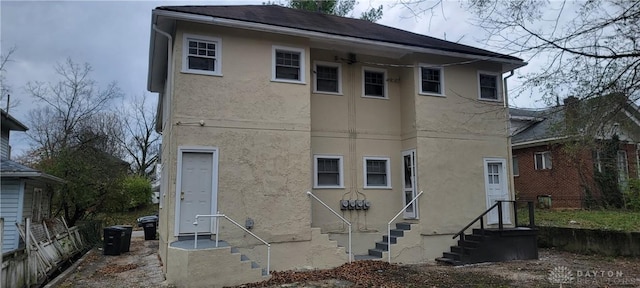 rear view of property featuring entry steps and stucco siding
