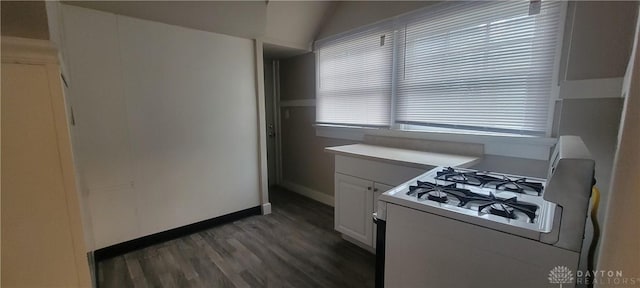 kitchen featuring baseboards, white gas range oven, light countertops, white cabinetry, and wood finished floors