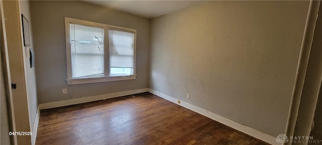 spare room featuring dark wood-style flooring and baseboards