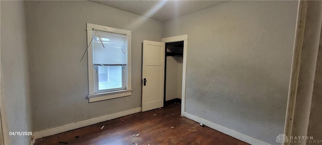 unfurnished bedroom featuring dark wood-style flooring and baseboards