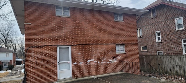 view of side of property featuring brick siding and fence