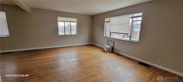empty room with visible vents, baseboards, and hardwood / wood-style flooring