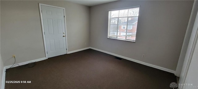 unfurnished room with dark carpet, baseboards, and visible vents