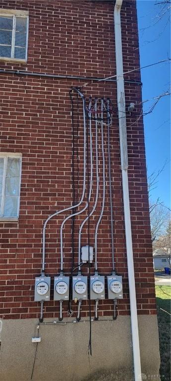 exterior details featuring electric meter and brick siding