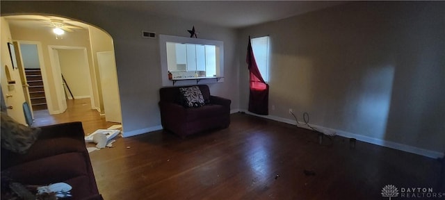 living area featuring baseboards, visible vents, arched walkways, and wood finished floors