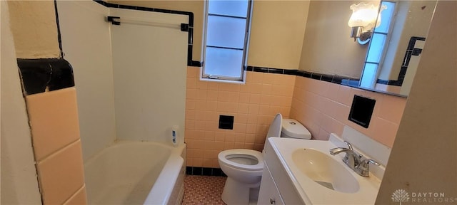 bathroom featuring tile patterned floors, a healthy amount of sunlight, toilet, and tile walls