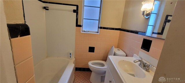 710 Rockford Ave Unit 704, Dayton, OH 45405 - bathroom featuring tile patterned floors, a healthy amount of sunlight, toilet, and tile walls