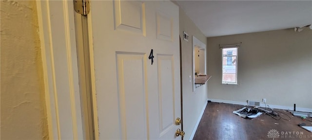 corridor with visible vents, dark wood-style floors, and baseboards
