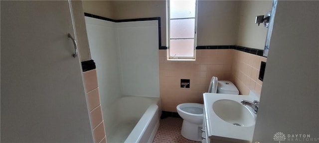full bathroom with tile walls, tile patterned floors, toilet, and vanity