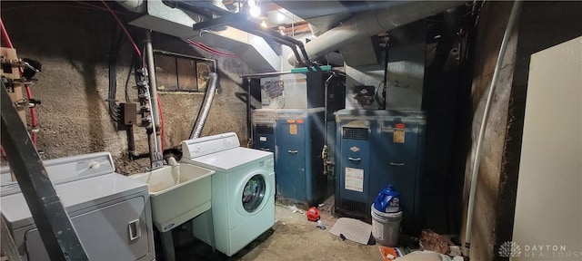 laundry room with heating unit, a sink, laundry area, and washer and clothes dryer