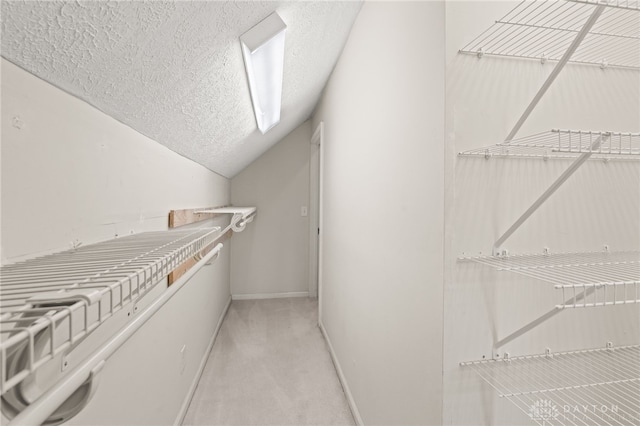 walk in closet featuring light colored carpet and vaulted ceiling