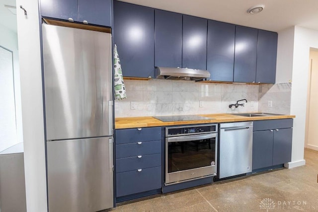 kitchen featuring blue cabinets, tasteful backsplash, butcher block countertops, under cabinet range hood, and appliances with stainless steel finishes
