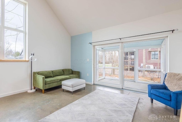 sitting room with baseboards, concrete floors, and high vaulted ceiling