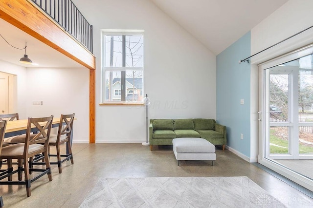 sitting room with concrete flooring, a wealth of natural light, and baseboards