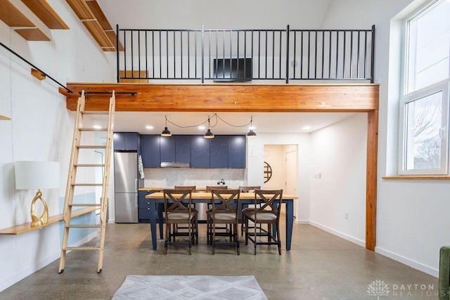 dining space featuring concrete flooring, a high ceiling, and baseboards