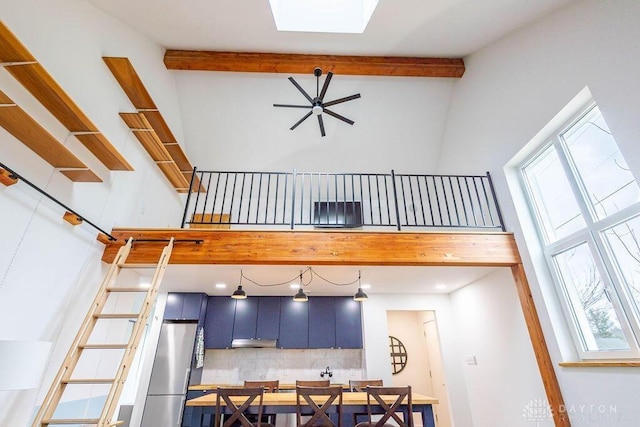 interior space featuring backsplash, a high ceiling, a healthy amount of sunlight, and freestanding refrigerator