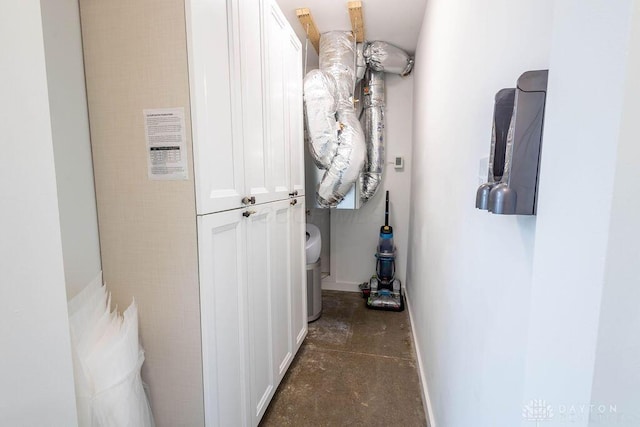 corridor featuring concrete flooring and baseboards