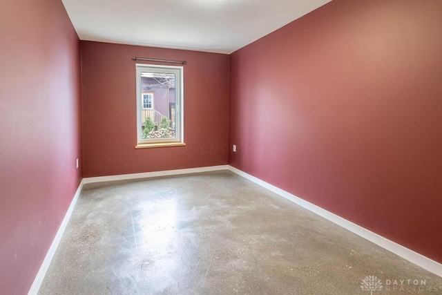 spare room featuring concrete flooring and baseboards