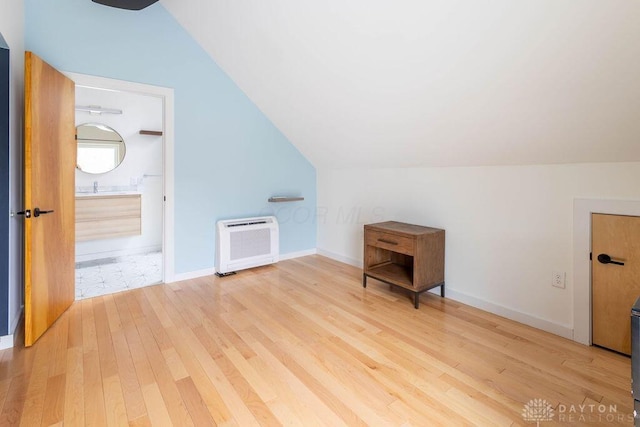 bonus room featuring lofted ceiling, baseboards, heating unit, and wood finished floors