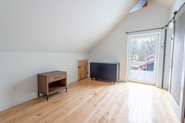 additional living space with a barn door, lofted ceiling, baseboards, and wood finished floors