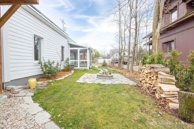 view of yard with a sunroom, a patio, and an outdoor fire pit