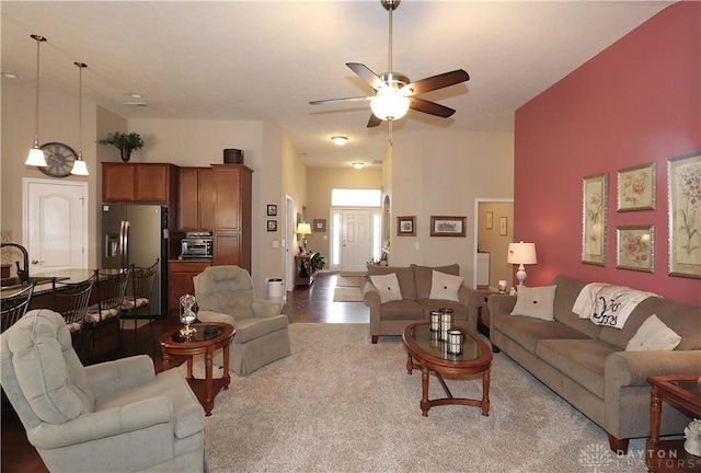 living room with a ceiling fan, a toaster, and light colored carpet