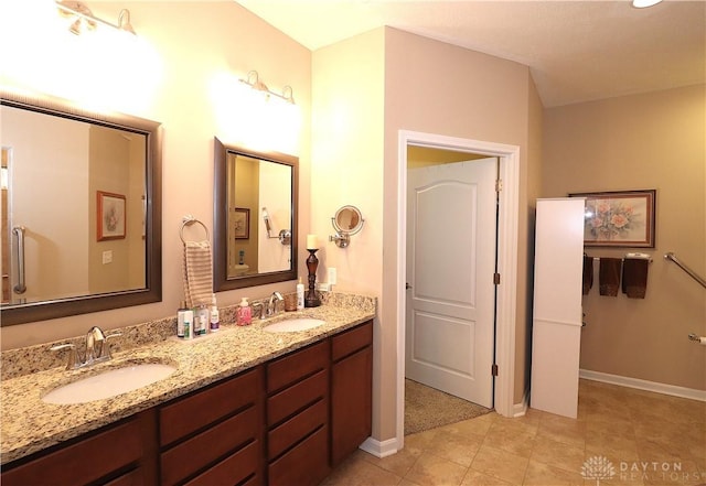 full bath with tile patterned flooring, baseboards, a sink, and double vanity