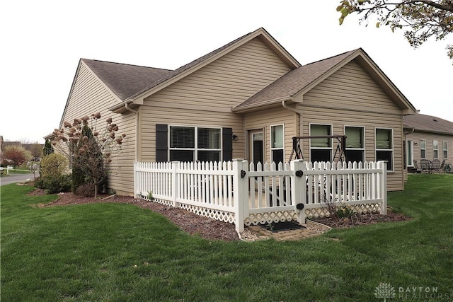 view of front of house with fence, roof with shingles, and a front yard
