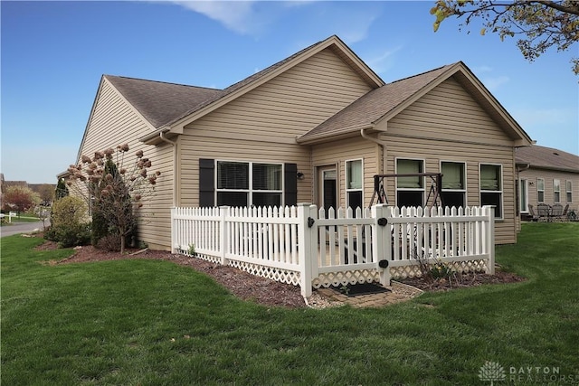 view of front facade with a front lawn, fence, and a shingled roof