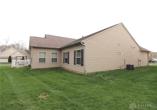view of property exterior featuring cooling unit, a yard, and roof with shingles