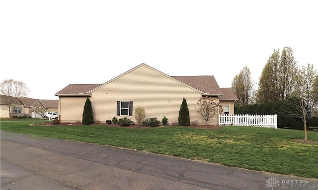 view of side of home with a yard and fence