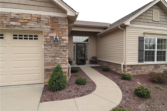 entrance to property featuring stone siding, a shingled roof, and a garage