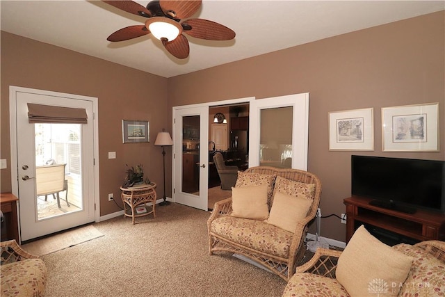 living area with light carpet, french doors, baseboards, and ceiling fan