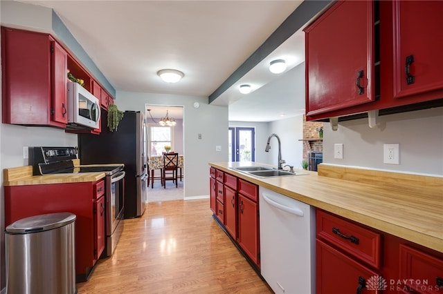 kitchen featuring a sink, wood counters, white appliances, light wood-type flooring, and an inviting chandelier