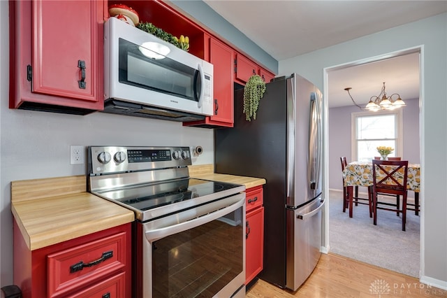 kitchen with light countertops, light wood-style floors, appliances with stainless steel finishes, and a notable chandelier