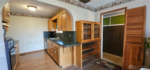 305 S Ada Doty St, Gratis, OH 45330 - kitchen featuring black oven, a sink, dark countertops, wood finished floors, and arched walkways