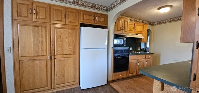 305 S Ada Doty St, Gratis, OH 45330 - kitchen with black appliances, arched walkways, under cabinet range hood, dark wood-type flooring, and dark countertops
