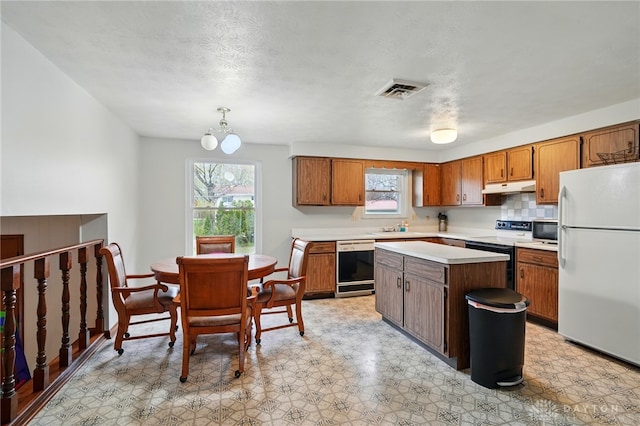 kitchen with electric range, freestanding refrigerator, dishwashing machine, light countertops, and under cabinet range hood