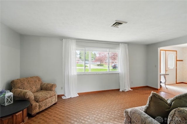 living area featuring baseboards and visible vents