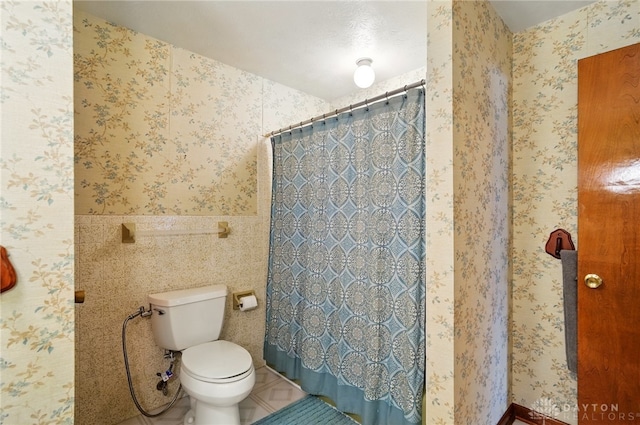 full bath featuring a shower with shower curtain, wallpapered walls, tile patterned flooring, and toilet