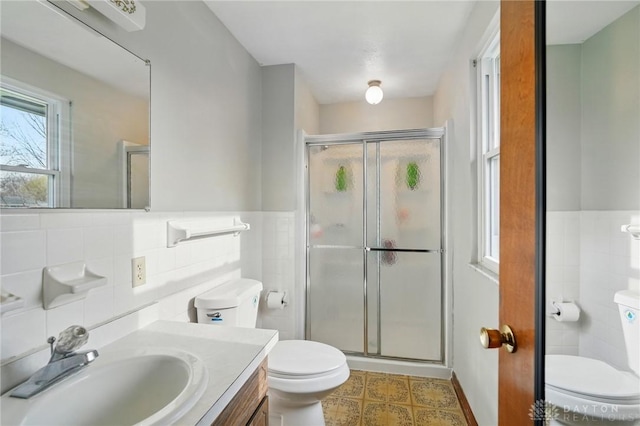 full bathroom with tile walls, a stall shower, vanity, and toilet