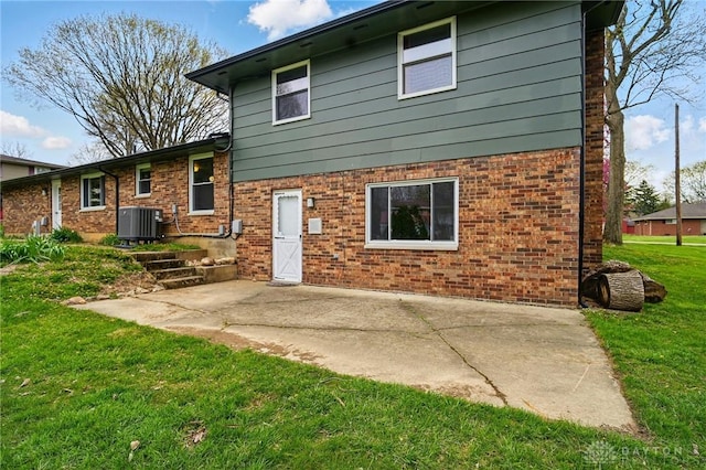 back of house featuring central air condition unit, brick siding, a yard, and a patio