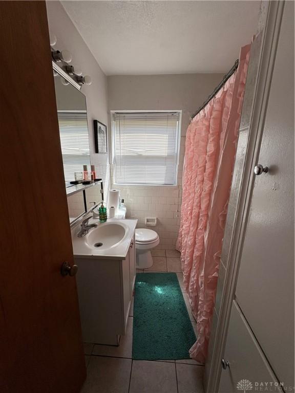 349 Orchard Dr, Oakwood, OH 45419 - bathroom with tile patterned flooring, toilet, vanity, tile walls, and a textured ceiling