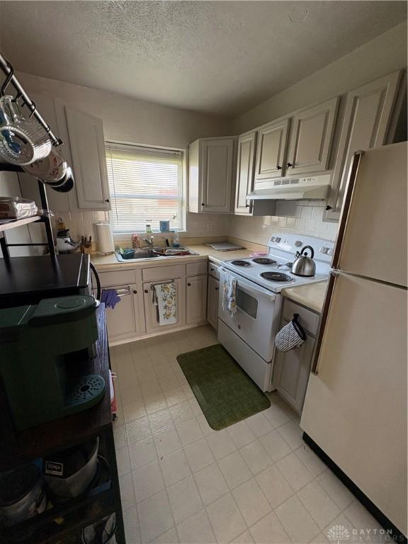 349 Orchard Dr, Oakwood, OH 45419 - kitchen featuring a textured ceiling, a sink, white appliances, light countertops, and under cabinet range hood