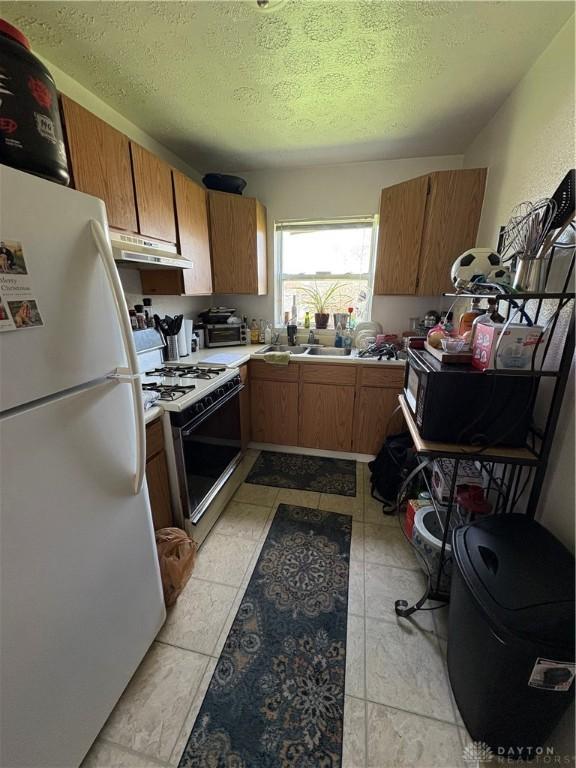 349 Orchard Dr, Oakwood, OH 45419 - kitchen with a textured ceiling, white appliances, brown cabinetry, light countertops, and under cabinet range hood