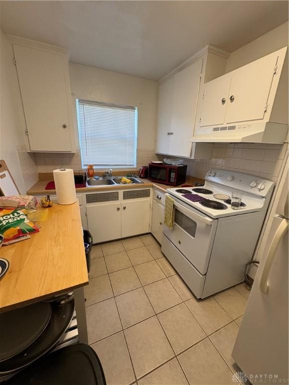 349 Orchard Dr, Oakwood, OH 45419 - kitchen featuring light tile patterned floors, a sink, white range with electric cooktop, black microwave, and white cabinetry
