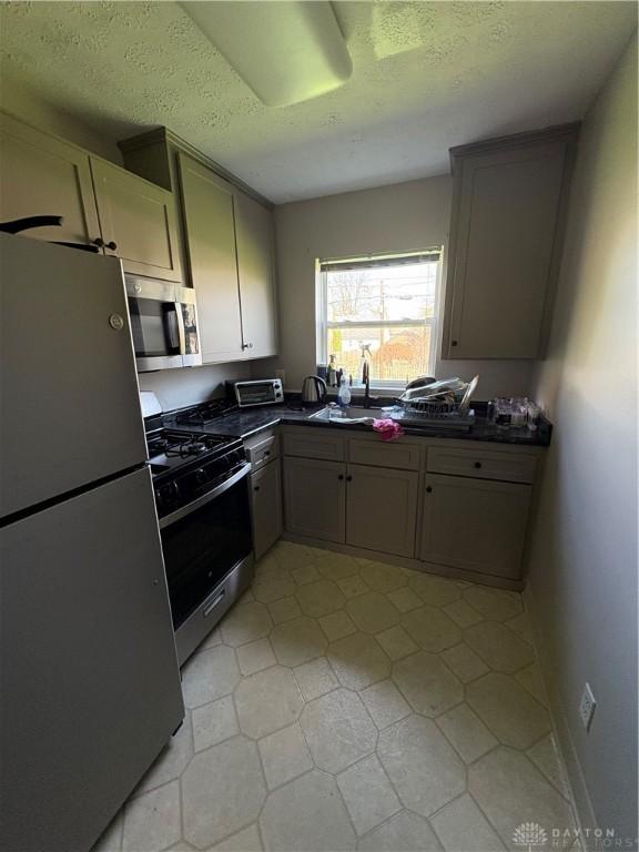 349 Orchard Dr, Oakwood, OH 45419 - kitchen with dark countertops, a sink, a textured ceiling, and appliances with stainless steel finishes