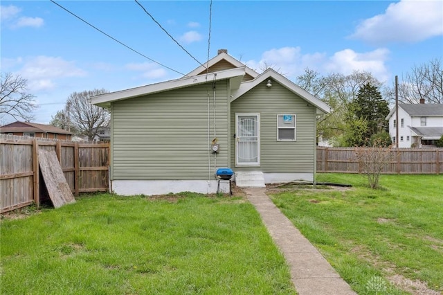 rear view of house with a yard and a fenced backyard