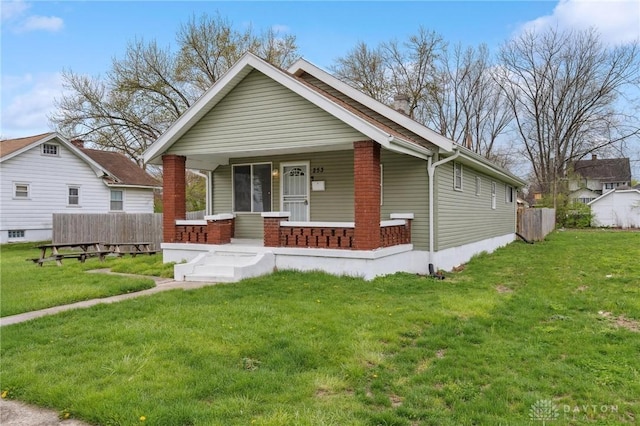 bungalow featuring a front lawn, fence, and covered porch