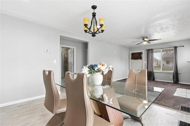 dining room featuring wood finished floors, visible vents, baseboards, and ceiling fan with notable chandelier